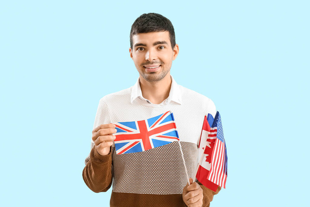 Young man with different flags on blue background - Foto, Imagen