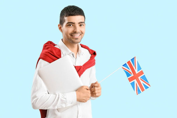 Young man with UK flag and laptop on blue background - Фото, зображення