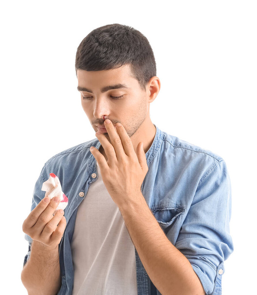 Young man with nosebleed and tissue on white background - Foto, Imagen