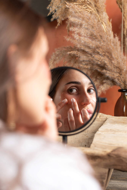 Reflection of woman applying under-eye patch at dressing table closeup. Professional facial skin care. Antiaging and refreshing cosmetic products - Valokuva, kuva