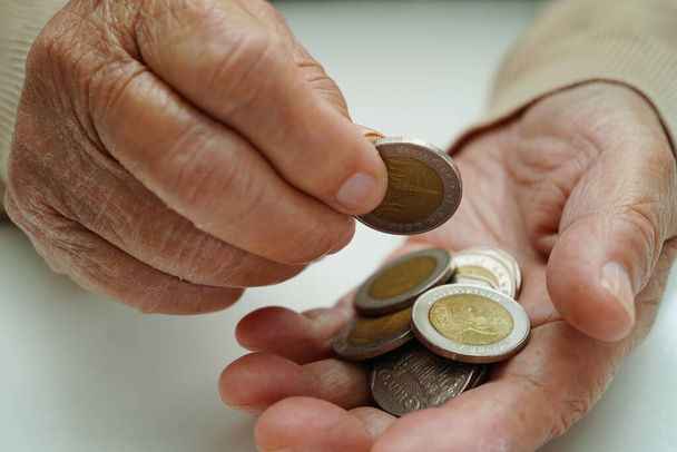 Retired elderly woman counting coins money and worry about monthly expenses and treatment fee payment. - Foto, afbeelding