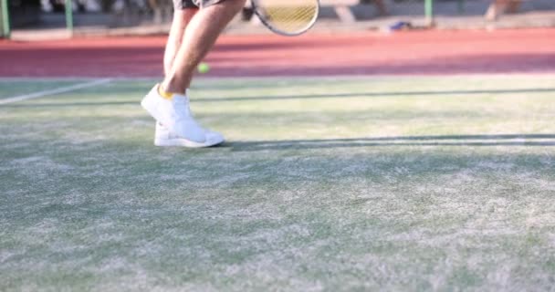 Bouncing ball near feet of tennis player on tennis court. Preparing serve in tennis match concept - Filmati, video