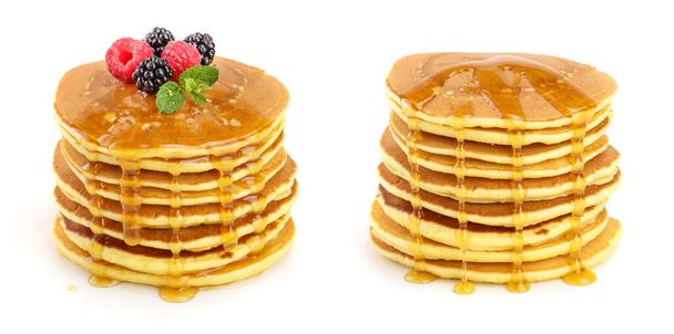 Pfannkuchen stapeln sich mit verschiedenen Beeren und Honig isoliert auf weißem Hintergrund. - Foto, Bild
