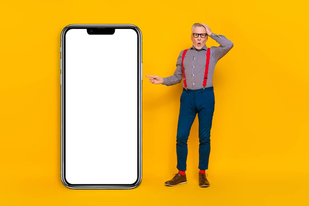 Full length body size view of handsome trendy stunned man demonstrating copy space app isolated over vivid yellow color background. - Fotografie, Obrázek
