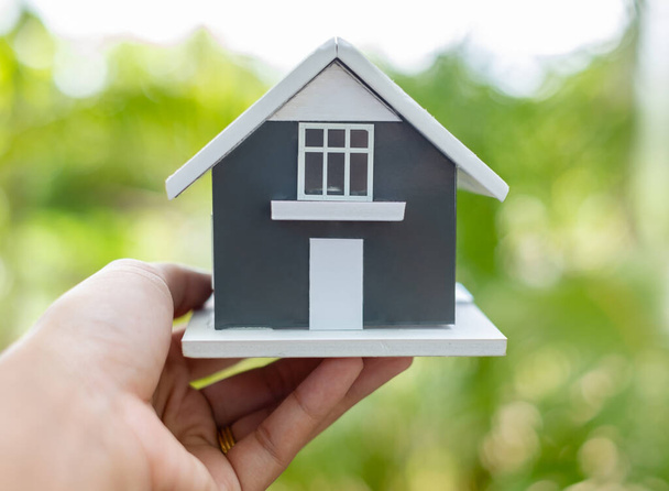 Concept d'assurance habitation. main tenant la maison modèle avec fond vert de la nature et l'espace de copie. - Photo, image