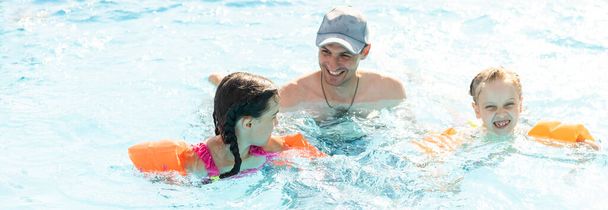 Szczęśliwa rodzina bawiąca się w basenie. Koncepcja wakacji letnich. - Zdjęcie, obraz