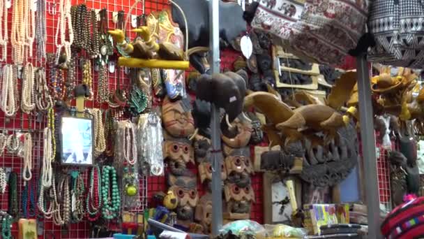 Vásároljon Thaiföldön szuvenírekkel, maszkokkal, fából készült díszekkel. Utcai fülke szobrokkal az emlékezetért. Bangkok utcái. A gyöngyök kézzel készültek. Ázsia. - Felvétel, videó