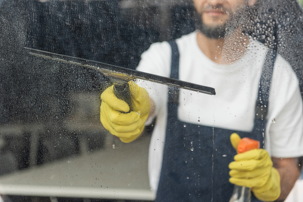 cropped view of man with detergent and window wiper washing glass in office - Foto, immagini