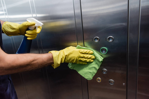 partial view of man in rubber gloves cleaning metallic elevator  - Photo, Image
