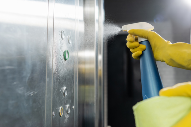 częściowy widok człowieka rozpylania detergentu podczas czyszczenia windy - Zdjęcie, obraz