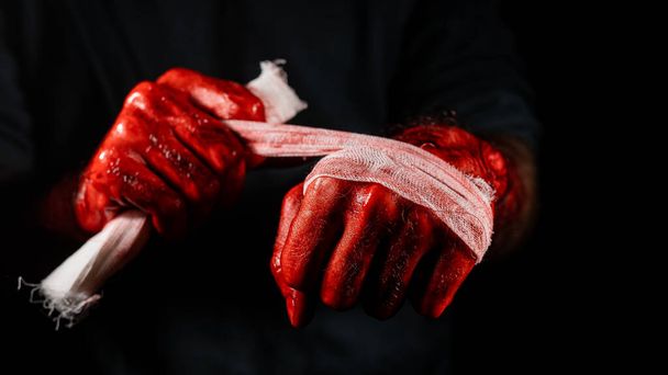 Een man bedekt met bloed verbandt zijn handen - Foto, afbeelding