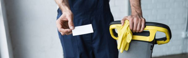 visão parcial do homem com cartão de visita em branco perto de máquina de limpeza de piso profissional, banner - Foto, Imagem