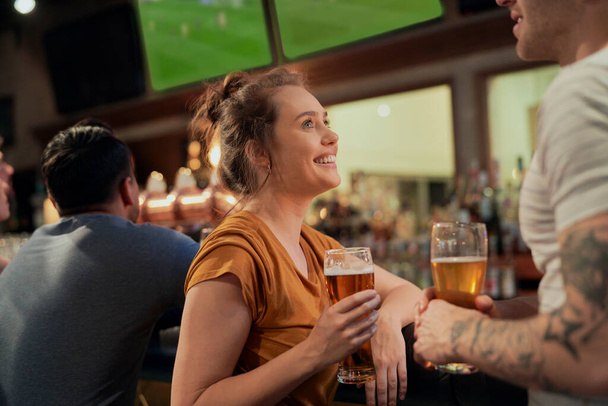 Woman drinking beer in bar and talking with man  - Foto, Imagem