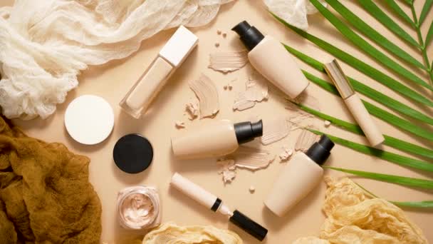 Bottles of three different shades of makeup foundation on beige background with palm leaf. Top view, flat lay - Materiał filmowy, wideo