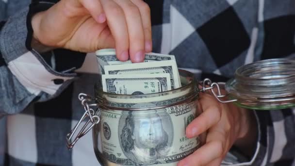 Dollar banknote saving money in glass jar. Unrecognizable woman moderate consumption and economy Collecting money. Tips. Business, finance, saving, banking and people concept. Extra money, passive - Materiał filmowy, wideo