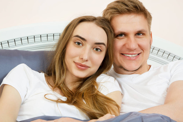 ポートレート若い美しい白いカップルがベッドの中で一緒に横たわっています – ティーン愛する家族 - 写真・画像