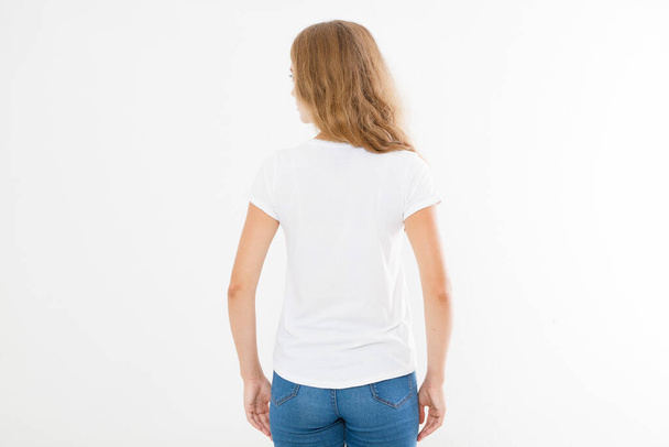 若い白人、ヨーロッパ人の女性、白いTシャツを着た女の子の背中のビュー。Tシャツのデザインや人のコンセプト。シャツのフロントビューの白い背景に隔離された。モックアップ。スペースのコピー. - 写真・画像
