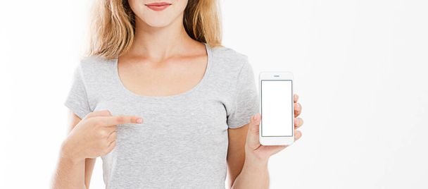 обрезанный портрет улыбающейся сексуальной женщины в футболке держать мобильный телефон, чистый экран мобильно указывая изолированные на белом фоне, копировать пространство. - Фото, изображение