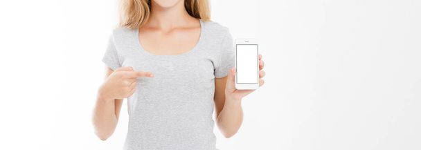 young girl, woman in t-shirt pointing finger at blank screen mobile phone isolated on white background. Hand holding smartphone. Copy space - Fotografie, Obrázek