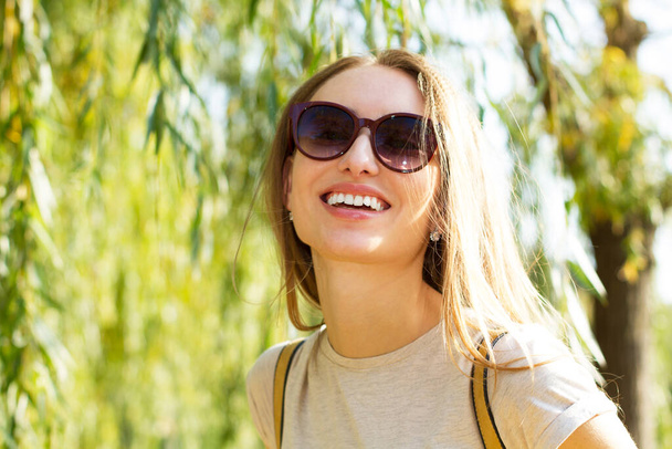 Hymyile onnellinen kesätyttö aurinkolaseissa puun alla puistossa lähikuva muotokuva, kesäkonsepti - Valokuva, kuva