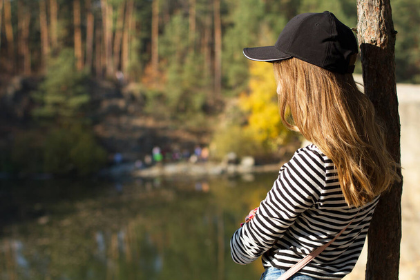 Rückseite Schöne junge Frau mit schwarzer Mütze auf einem Hintergrund des wilden Waldes Kopierraum, aktives Lebenskonzept - Foto, Bild