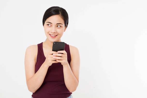 Sonriente asiática, mujer japonesa sostiene teléfono inteligente negro, teléfono celular aislado sobre fondo blanco. Copiar espacio. - Foto, imagen