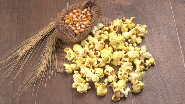 tas de délicieux pop-corn avec des graines de maïs cru en sac sur la table en bois. - Photo, image