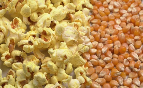 Hromada solného popcornu se surovými kukuřičnými semínky na dřevěném stole. - Fotografie, Obrázek