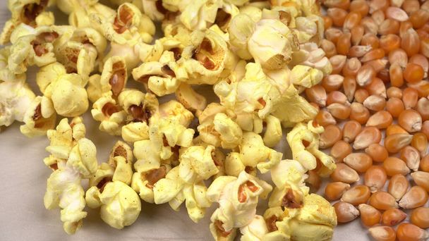 Hromada solného popcornu se surovými kukuřičnými semínky na dřevěném stole. - Fotografie, Obrázek