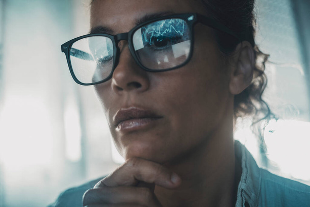 Technology concept people portrait with digital charts reflected on eyewear. One woman in business online modern activity looking a display with reflection on glasses. Concept of businesswoman alone - Fotó, kép