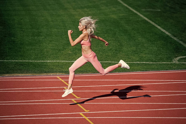 athletic lady compete in sprint. sport healthy lifestyle. fitness training outdoor. runner run fast on running track. energetic and sporty. marathon speed energy. woman in motion. - Valokuva, kuva