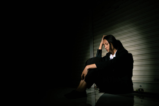 Woman depressed from sad stress pain despair problem, person sit on closed shop on corridor alone with emotion lonely desperate upset head down. Head in hand no way out concept, copy space - 写真・画像