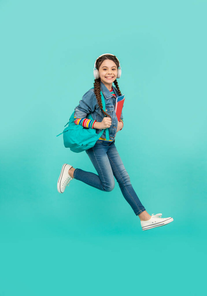 Happy girl jumping blue background, education. Energetic teenage girl in midair. School education. Informal and non-formal education. - Foto, imagen