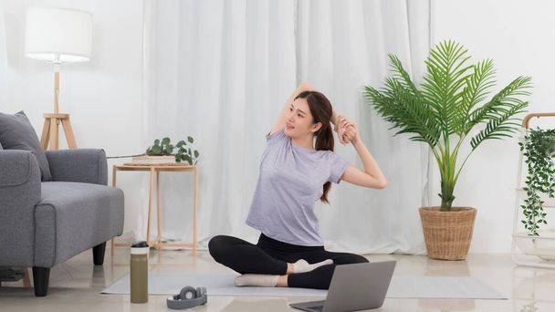 Yoga exercise concept, Asian woman hold hands behind back to stretching before yoga training online. - 写真・画像