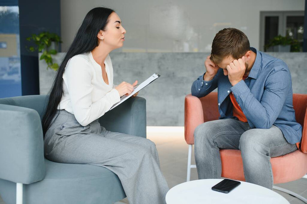 psychology, mental therapy and people concept - woman psychologist talking to sad young man patient at psychotherapy session - Photo, Image