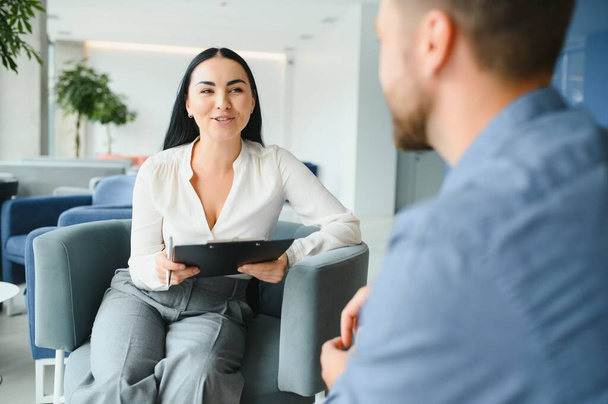 Business concept. Young dark-haired woman sitting in front of mature cheerful office manager on job interview, having relaxing talk about her experience and study degree - Photo, image