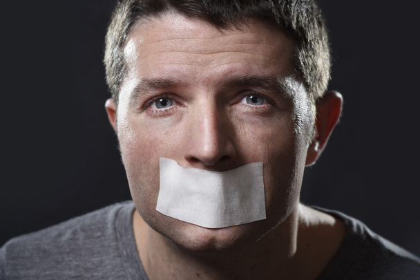 attraente giovane uomo con la bocca sigillata su nastro adesivo per impedirgli di parlare
 - Foto, immagini