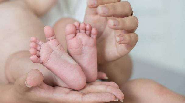Eltern halten Füße von Neugeborenem in den Händen. - Foto, Bild