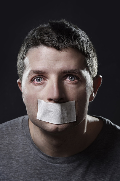 aantrekkelijke jonge man met mond verzegeld op plakband om te voorkomen dat hem spreken - Foto, afbeelding