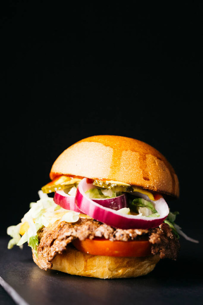 Doble cheeseburger with vegetables over a black background - Fotó, kép