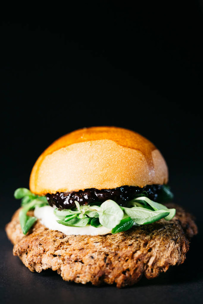 Doble burger with blueberries, vegetables and cheese over a black background - Foto, Bild