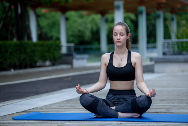Beautiful women sportswear practicing yoga sitting pose stretching legs and folded hands. Prayer position yoga outdoor on floor. Relaxation yoga exercise concept. - Foto, Bild