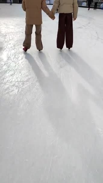 Люди катаються на ковзанах під відкритим небом в місті в зимовий день. Люди катаються на ковзанах. Ноги, спина, каток. Зимові свята, заходи, відпочинок, відпочинок, спорт. Вертикальне відео
 - Кадри, відео
