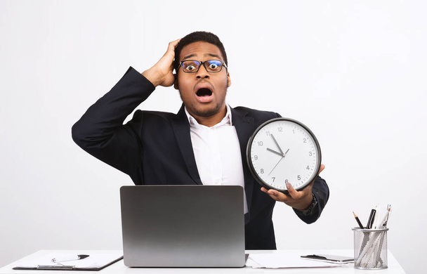 Deadline. Shocked Black Businessman Holding Clock Sitting At Laptop Computer Looking At Camera In Shock Over White Studio Background. Time Mangaement Problem Concept - Foto, Imagem