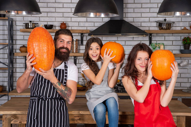 happy parents with kid cook pumpkin together in kitchen, family. - Φωτογραφία, εικόνα