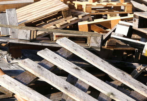 houten pallets opgestapeld in een stortplaats - Foto, afbeelding