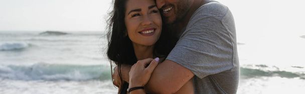 homme joyeux étreignant petite amie souriante près de l'océan en portugais, bannière - Photo, image