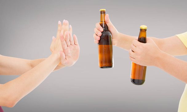 vrouwelijke hand verwerpen een fles bier geïsoleerd op grijze achtergrond.anti alcohol concept, kopieer ruimte.Zorgen voor jezelf, gezondheidszorg - Foto, afbeelding