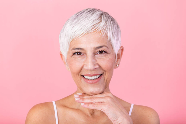 Portrait of a smiling senior woman looking at camera. Closeup face of mature woman after spa treatment isolated over grey background. Anti-aging concept. - Photo, Image