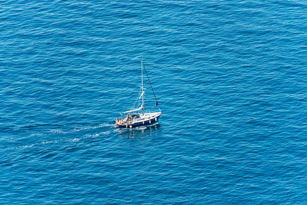 Aerial view of a small sailing boat with a small group of people on board, in the blue Mediterranean Sea, Gulf of La Spezia, Liguria, Italy, southern Europe. - Photo, Image